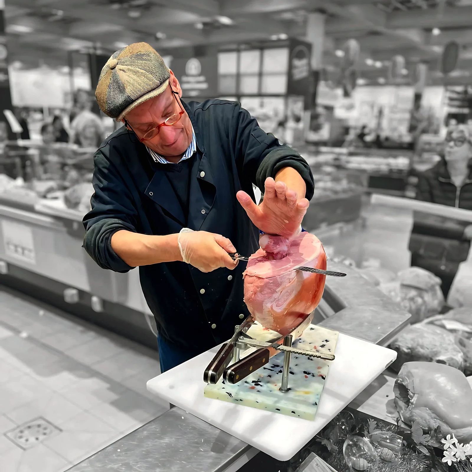 Animateur Défontaine tranchant un jambon à l'os au rayon charcuterie